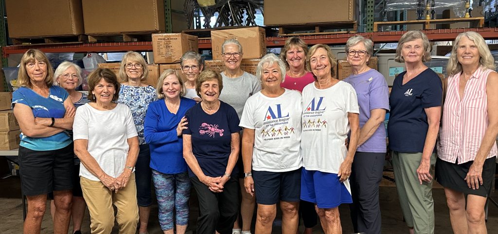 Assistance League Members unpack uniforms at the AACPS warehouse, helping students in need.