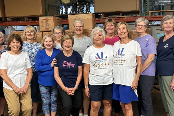 Assistance League Members unpack uniforms at the AACPS warehouse, helping students in need.